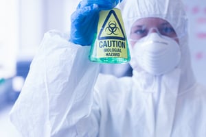 Close-up of a scientist in protective suit with hazardous blue chemical in flask at the laboratory-1